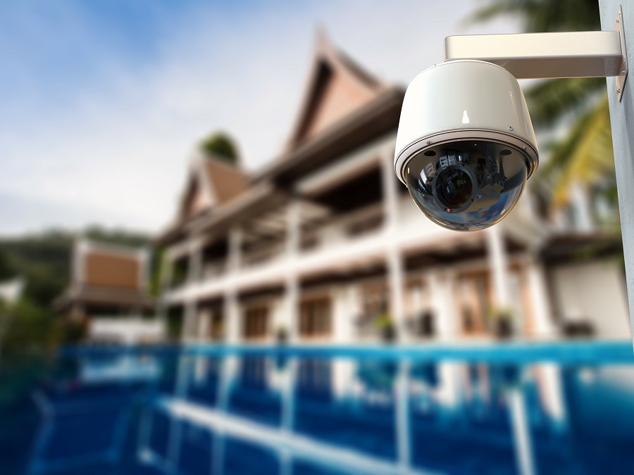 Sophisticated home surveillance camera with all-weather housing looks over luxury home grounds.